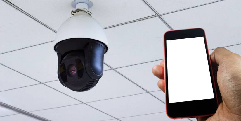 Ceiling security camera and a hand holding a smartphone