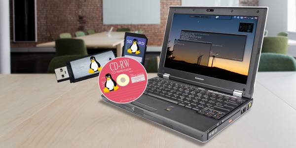 A laptop on a desk behind images of various disk media with the Linux penguin logo printed on them.