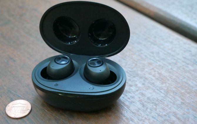 Tranya T10 true wireless in-ear headphones in their Qi wireless charging case with a penny for scale