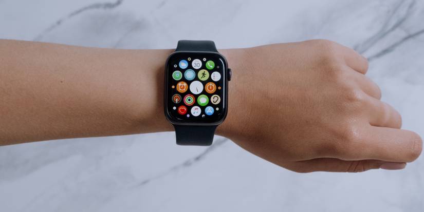 A hand in a fist has an Apple Watch on its wrist with all of its apps visible