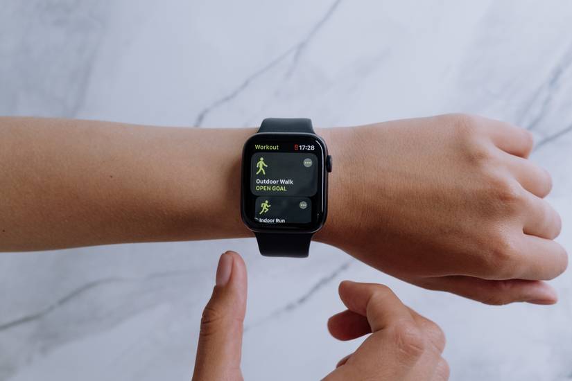 The Workout app open on an Apple Watch worn on a wrist. A hand moves towards the Watch to adjust something