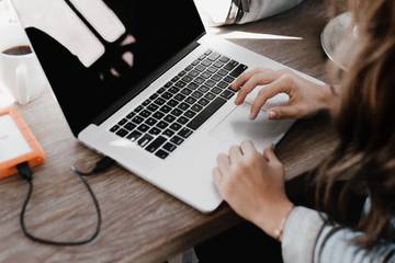 A person using a MacBook with an external hard drive plugged into it