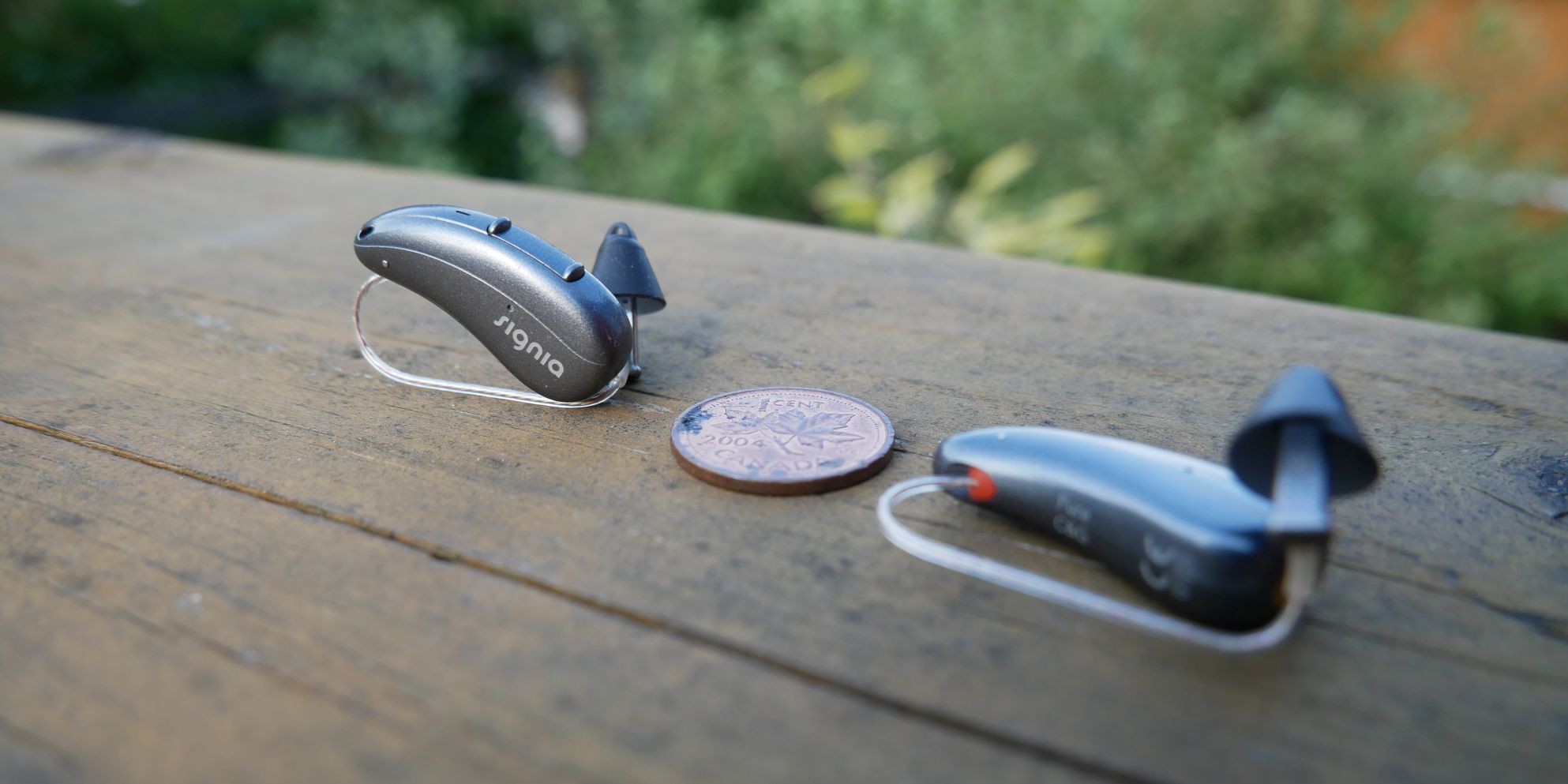 Signia Pure Charge&Go AX hearing aids with penny for size reference.