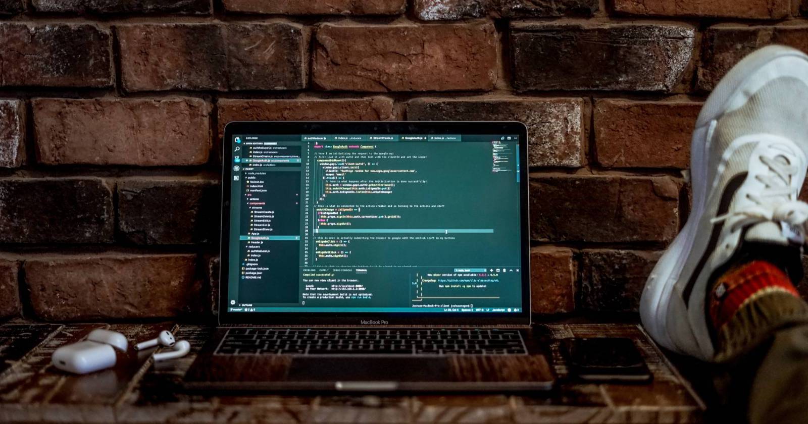 Laptop on brick wall displaying code