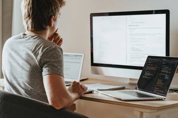 Programmer at desk with laptops and monitor
