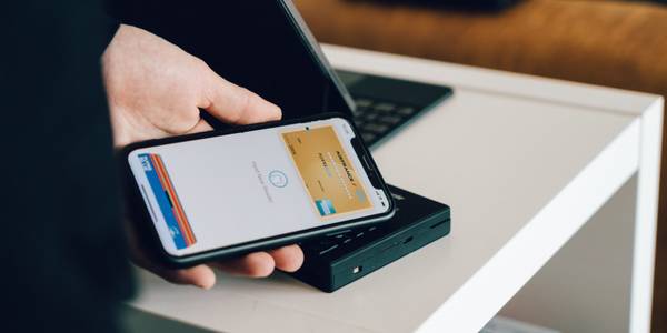 person checking out on a small terminal using Apple Pay on an iPhone