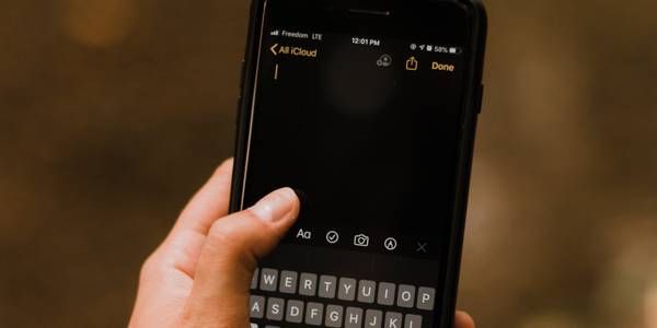 hand holding iphone keyboard notes app