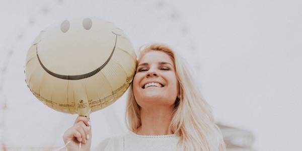 woman holding a smiley balloon