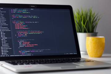 A laptop on a desk showing a page of code on a dark background