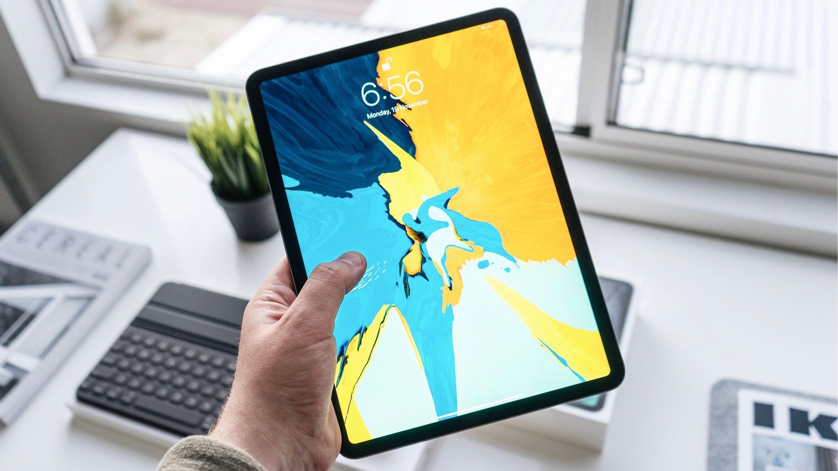Holding an iPad Pro with bright wallpaper