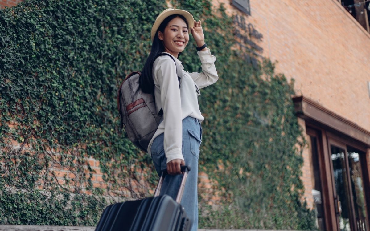 Feliz viajante feminina com mochila e bagagem