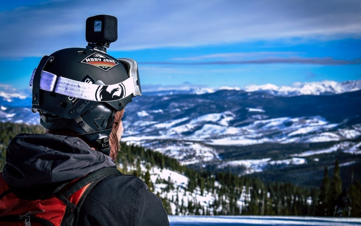 Homem de capacete com câmera de ação olhando para a montanha de neve