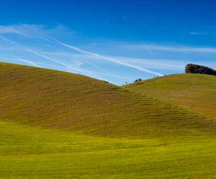 A brown grassy hill with a blue sky above