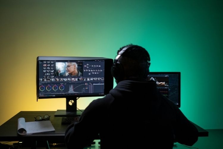 A man sitting in front of the computer while editing video