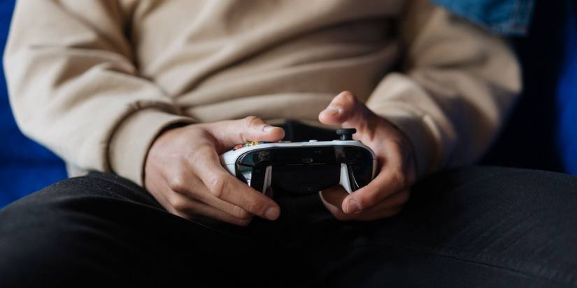 A person sat on the sofa holding an Xbox One controller