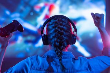person wearing headphones holding controller while gaming