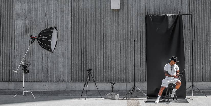 一名男子坐在背景幕布前,摄像机和灯光对着他