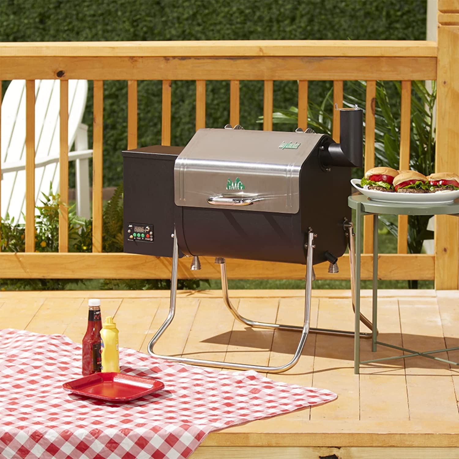 A Green Mountain Grills Davey Crockett Sense Mate outside on the patio next to a table of burgers