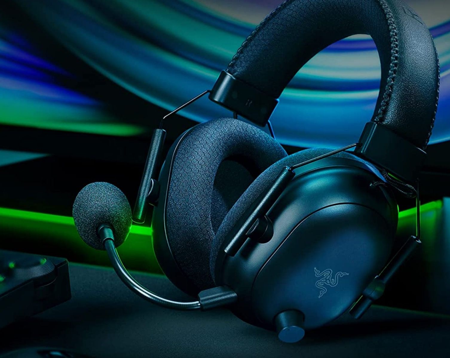 A sideshot of a pair of black Razer BlackShark V2 gaming headphones on a colorful vibrant background