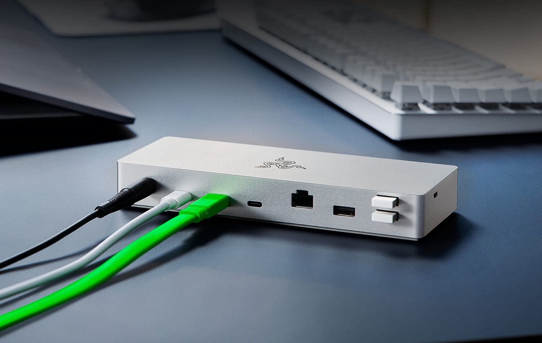 Razer Thunderbolt 4 dock for Mac with charging cabled connected sitting on a desk beside a keyboard