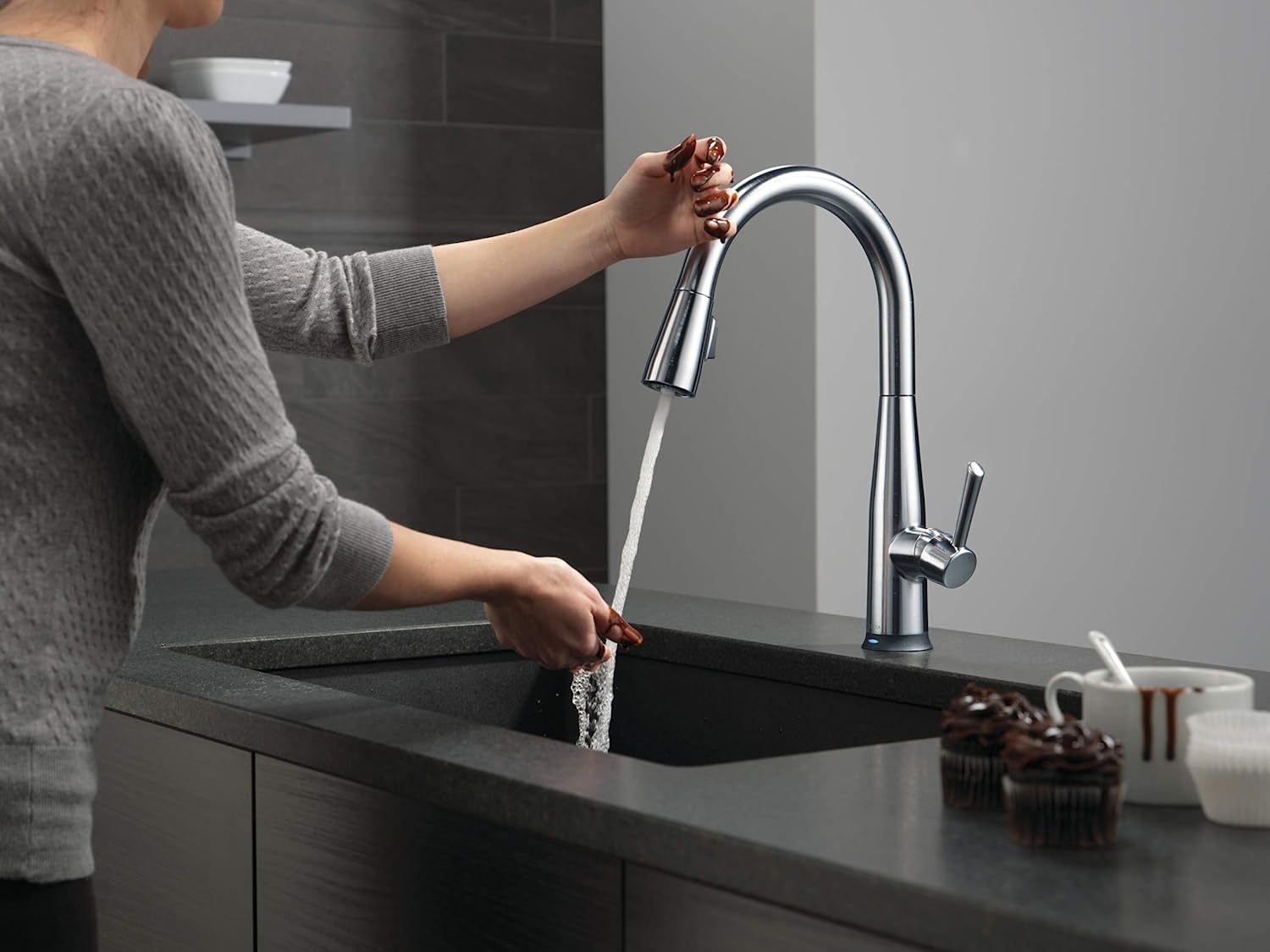 a person using touch to activate the delta faucet essa voiceiq kitchen faucet