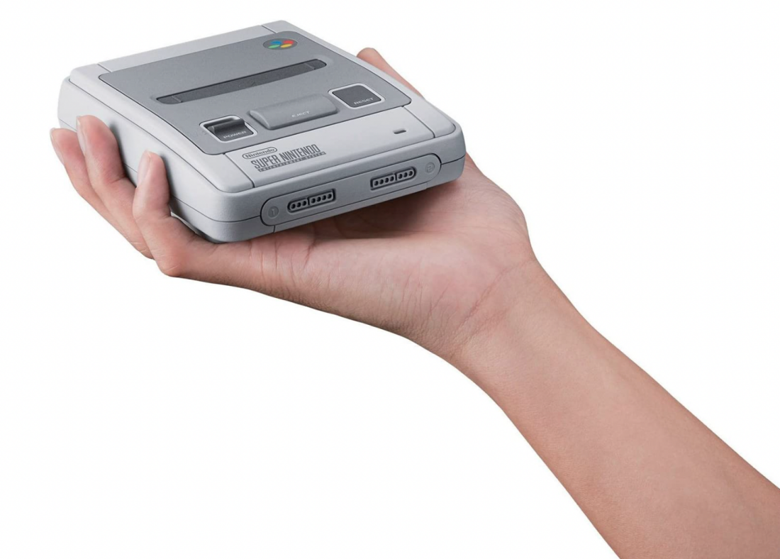 A shot of a Super Nintendo Entertainment System in someone's hand illustrating its size