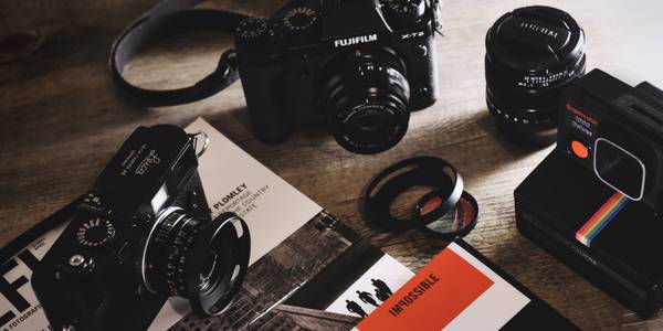 photo of a camera, lenses, and some books on a table