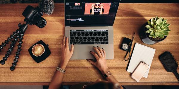 person editing on a laptop with a camera nearby