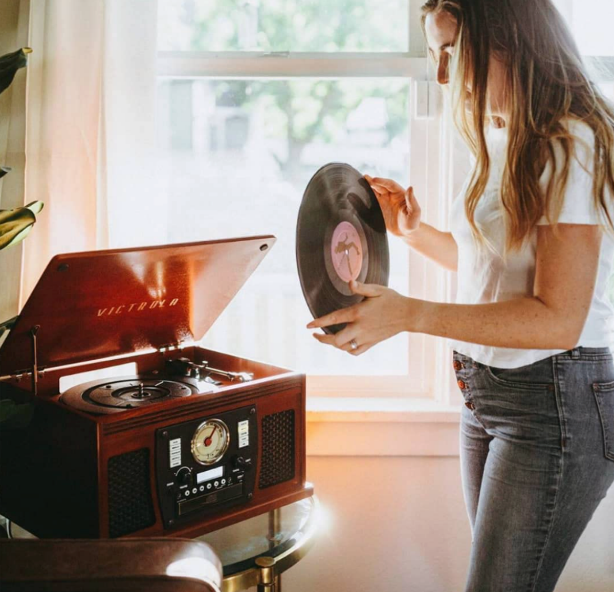 A woman putting a record on the Victrola 8-in-1 Record Player at home