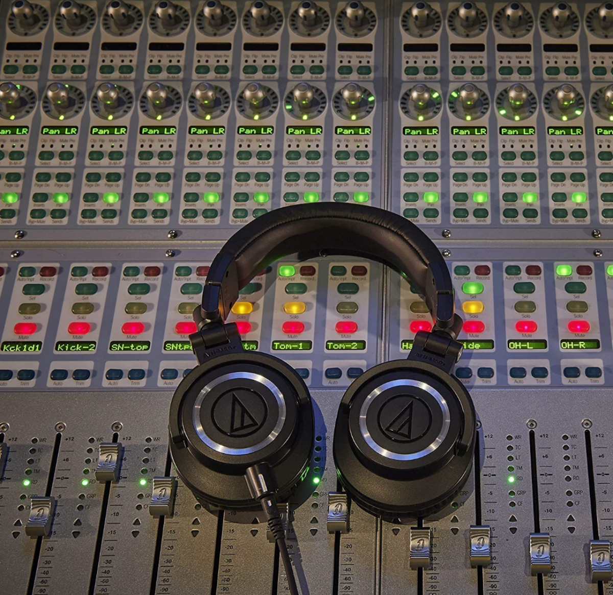 A pair of Audio-Technica ATH-M50X headphones laying on a mixing desk