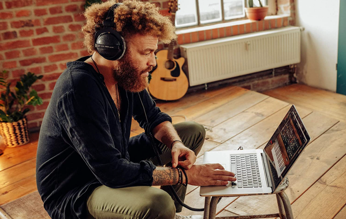 A music producer wearing a pair of Beyerdynamic DT 770 Pro headphones while producing music on his laptop