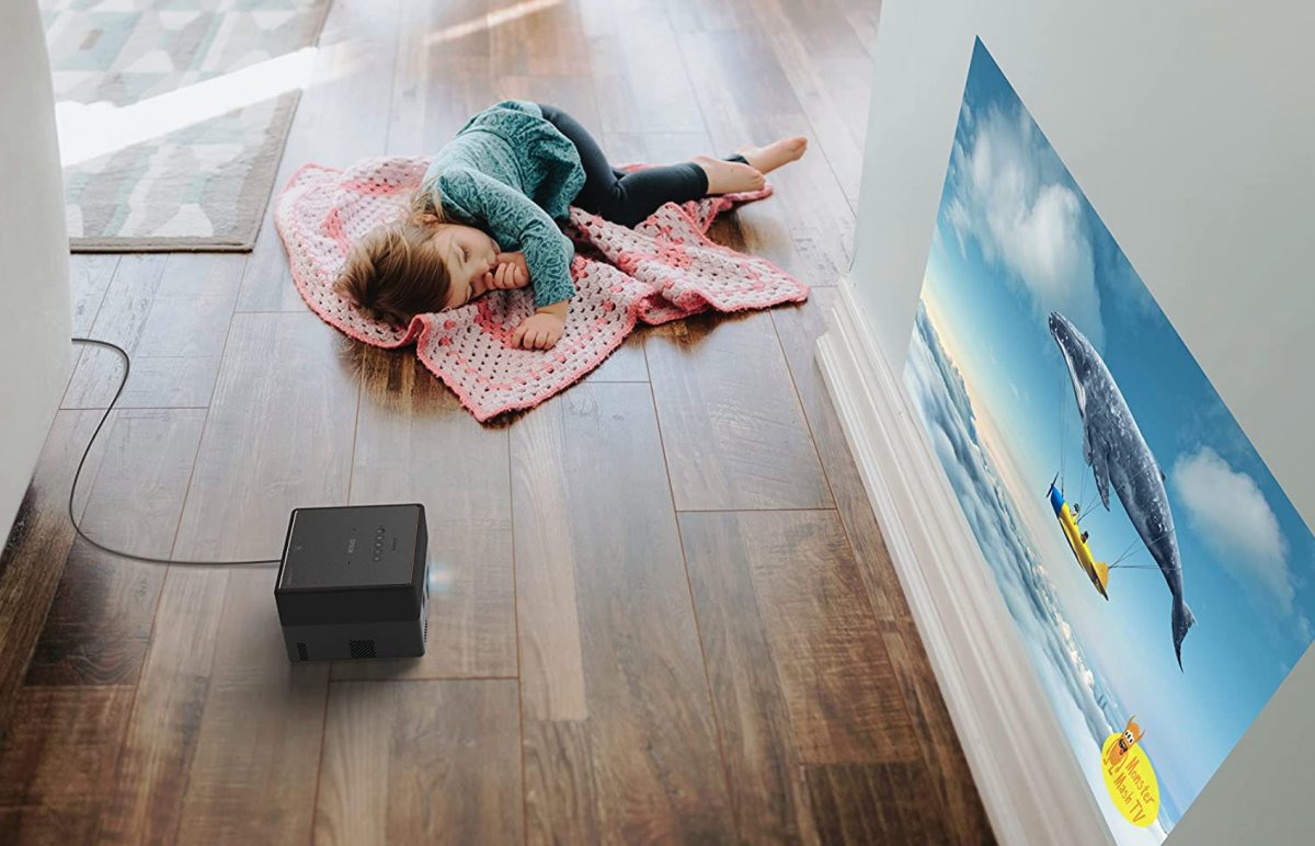 A child asleep on the floor next to a Epson EpiqVision Mini EF12 Smart Streaming Laser Projector