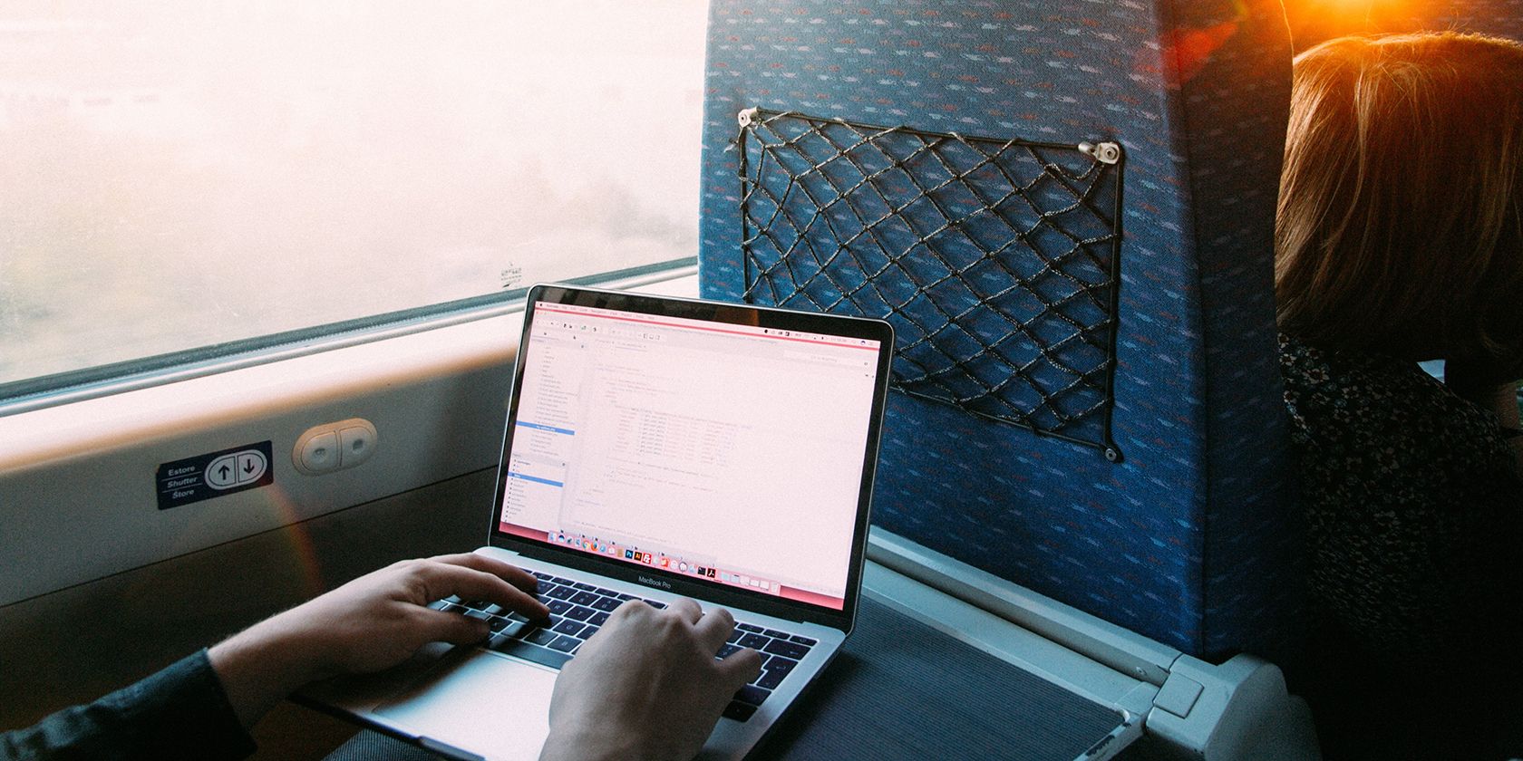 Person Using MacBook Pro While Traveling 
