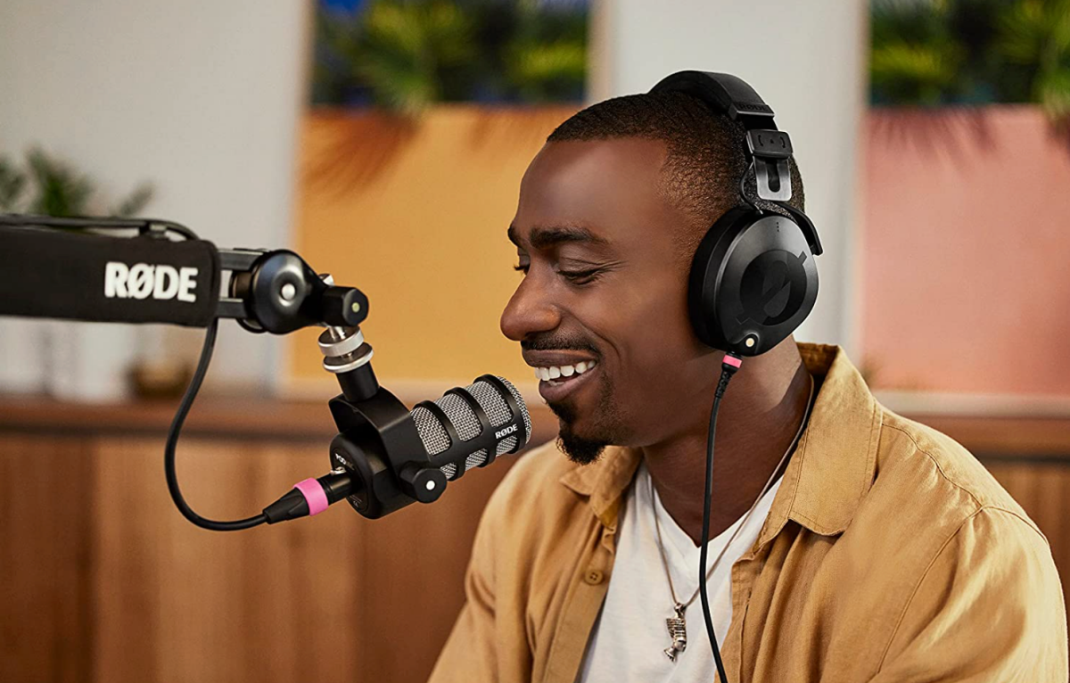 A man speaking into a RØDE microphone while wearing a pair of NTH-100 headphones