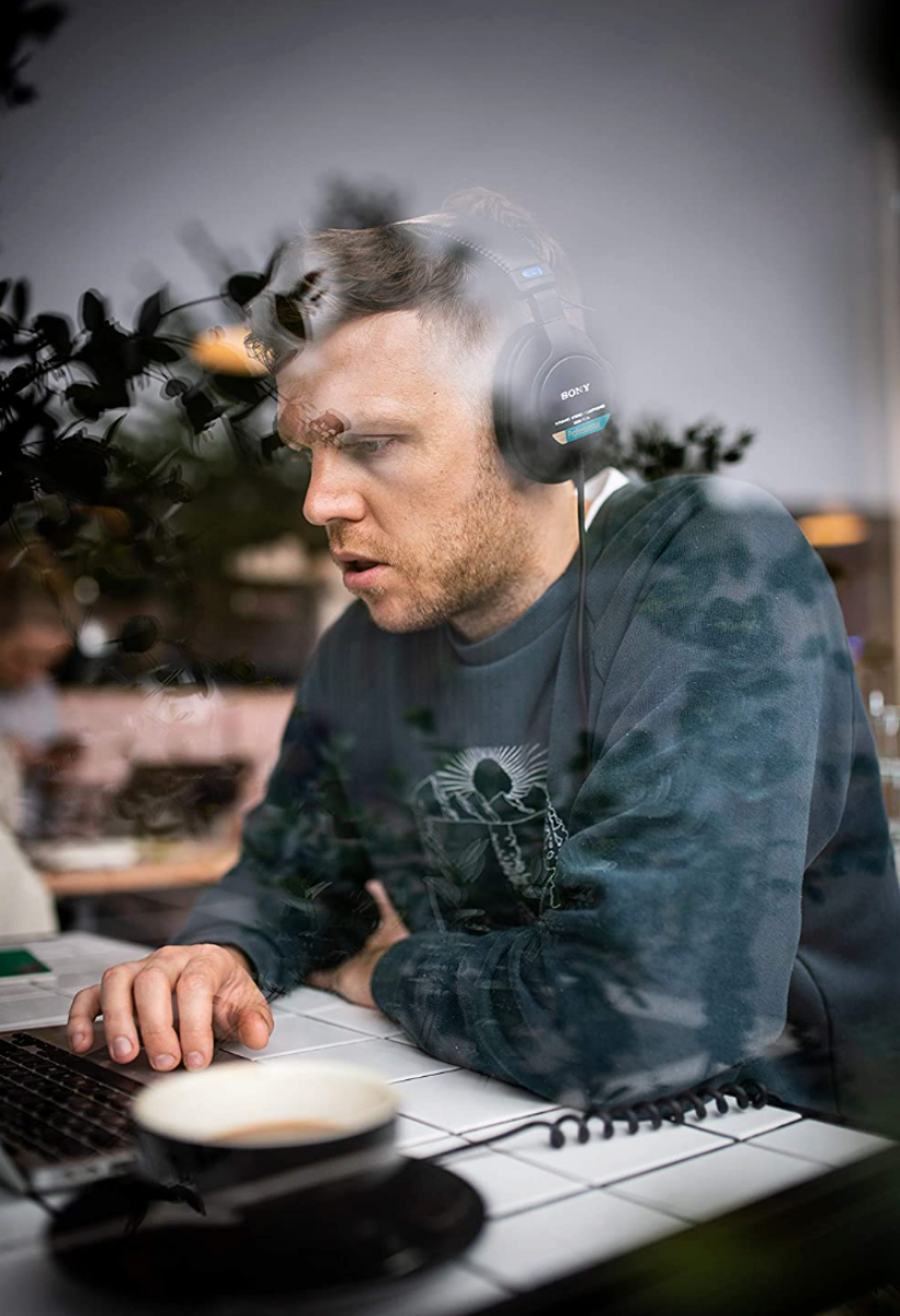 A man weating a pair of Sony MDR7506 Headphones while on his laptop