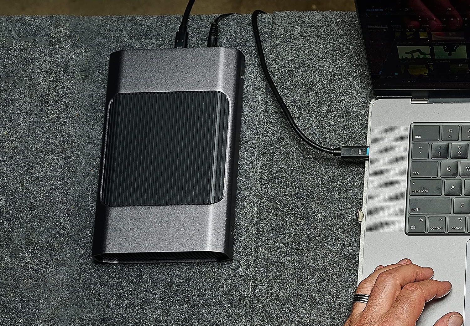 top-down view of the sandisk professional g-drive hdd, next to a macbook