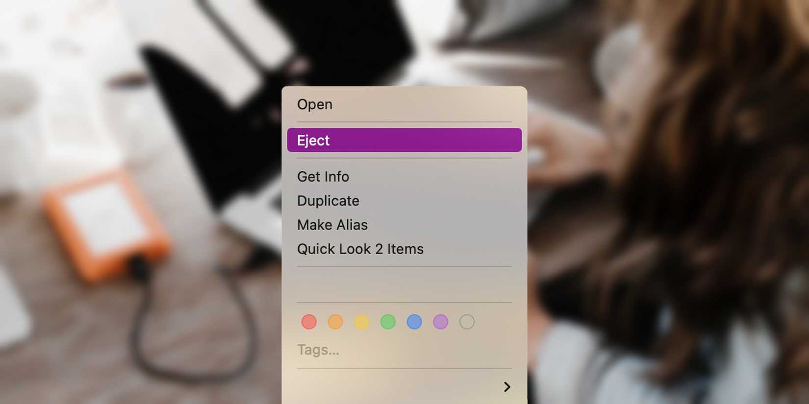 Blurred image of woman using external drive on her MacBook with an Eject dialog superimposed