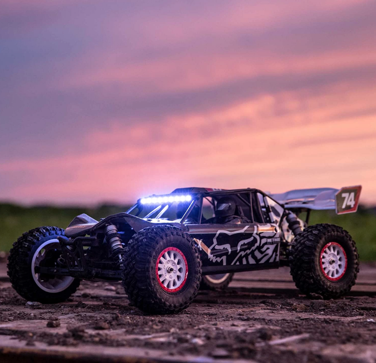 A Losi Tenacity DB Pro 4WD Desert Buggy with LED bar against a colorful sky