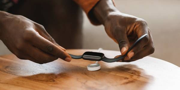 Person setting an Apple Watch on a charging puck