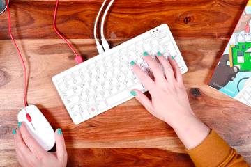 Hand on a mouse and Raspberry Pi 400 keyboard on a desk