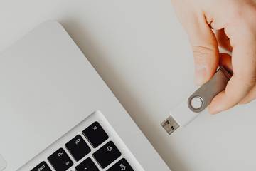 hand inserts flash drive into laptop