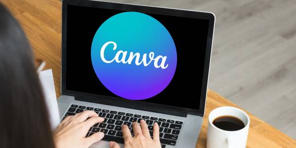 Woman working on laptop with Canva logo on screen. 