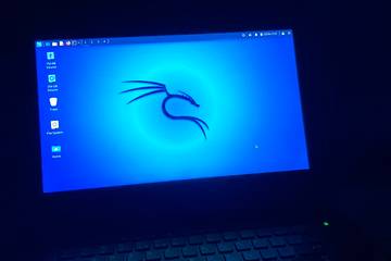 laptop running kali linux illuminates a dark room