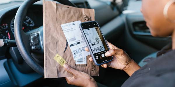 Person scanning QR Code on a parcel while sitting in a car