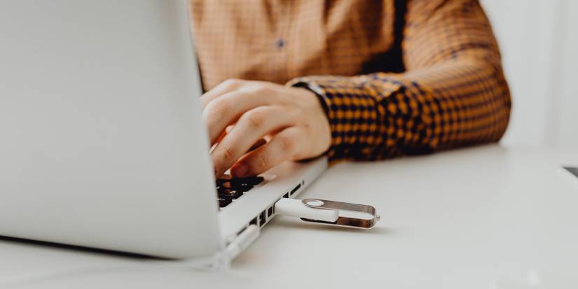 man uses laptop with usb drive plugged in