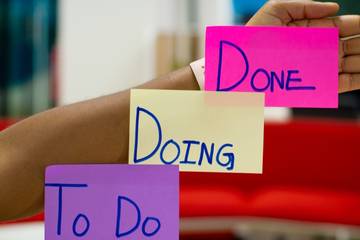 Person’s hands holding up sticky notes with text written on them