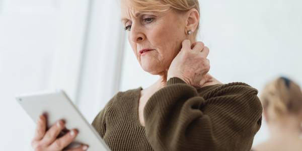 Elderly woman holding a tablet against a mirror