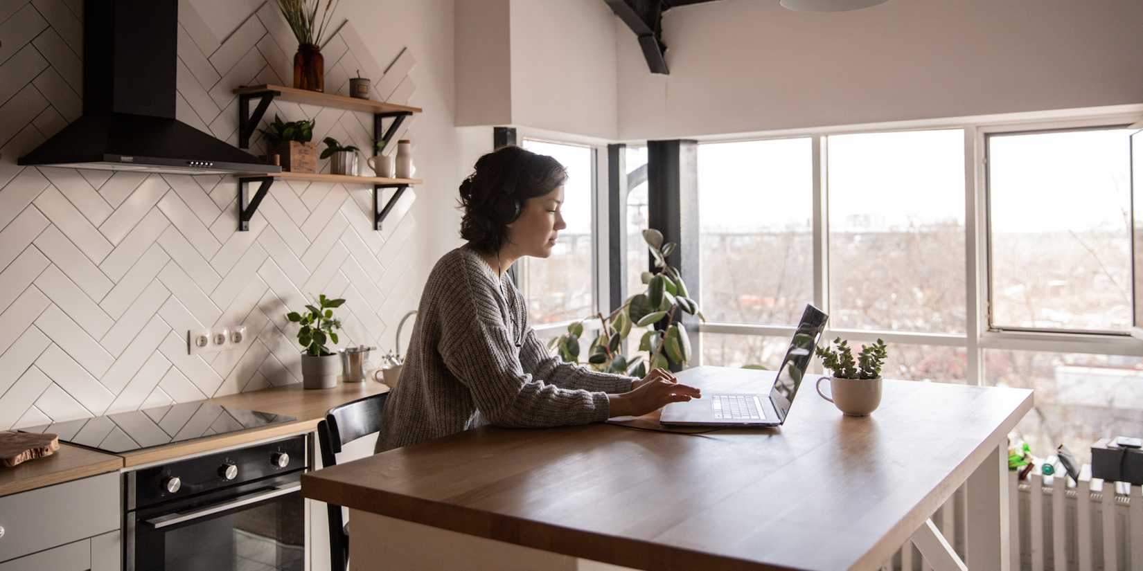 young woman using laptop while sitting at kitchen table