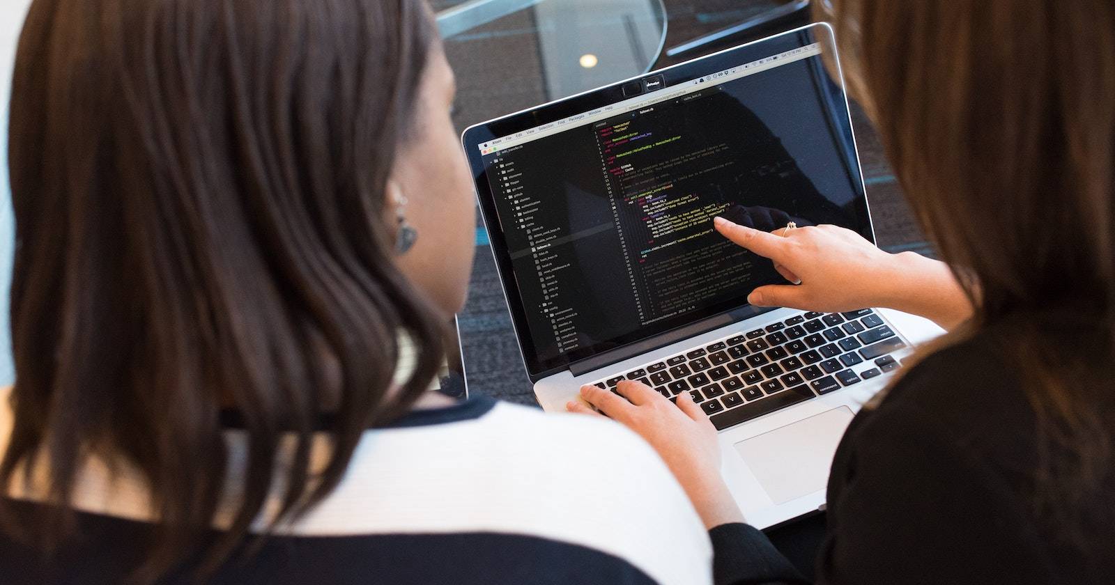 Two people looking at a laptop screen, one pointing at it with their other hand on the keyboard.