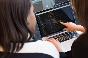 Two people looking at a laptop screen, one pointing at it with their other hand on the keyboard.